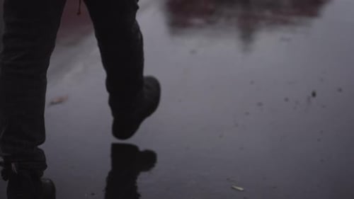 Mans Feet in Leather Shoes Walking on Wet Asphalt Road at the Rain