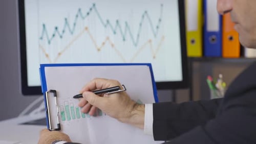 Close-up of businessman analyzing financial charts in company.
