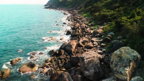 Gentle Waves Caressing Rugged Rocky Shoreline During Sunset Blending Turquoise Waters with Warm Hued