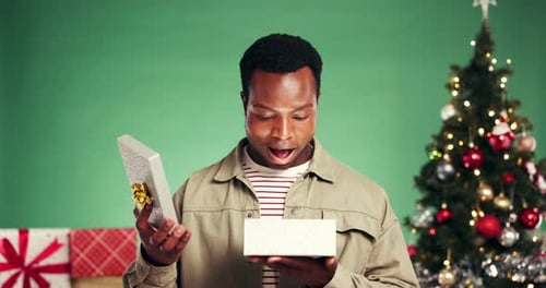 Christmas, gift and pointing with face of black man in studio for celebration