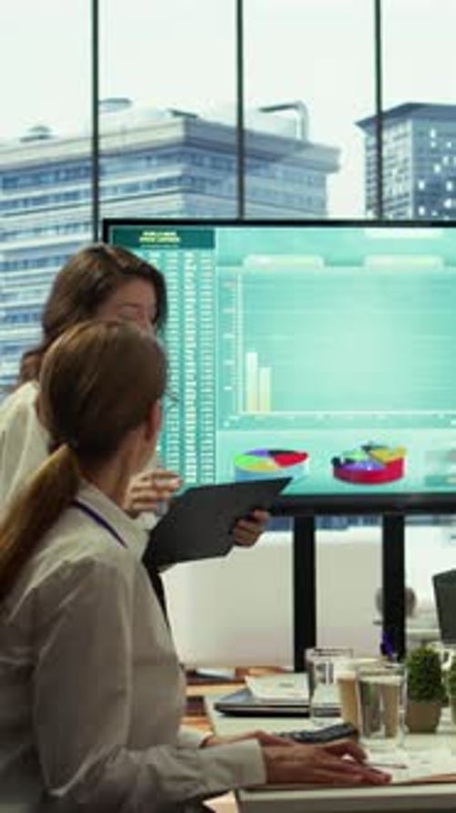 Professional Women Reviewing Data Presentation in Modern Office