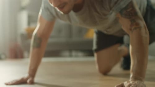 Close Up Shot of a Muscular Fit Man in T-shirt and Shorts is Doing Push Up Exercises While Using a