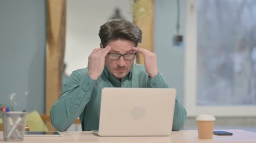 Man at Desk Rubbing Temples with Headache