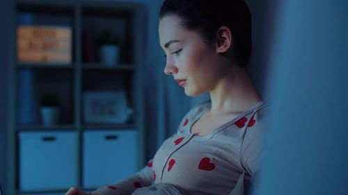 Woman uses laptop computer at night in bed