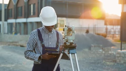 African American Surveyor Engineer Using Theodolite in a Modern Cottage Town