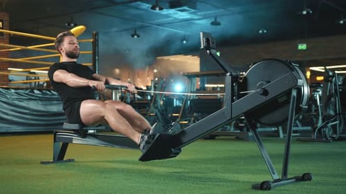 Dedicated Man Utilizing Rowing Machine for FullBody Workout in a Gym with Dynamic Lighting
