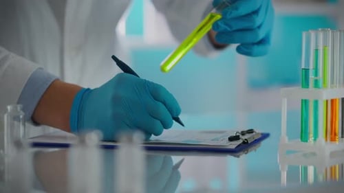 Entwicklung. Ein Wissenschaftler, Arzt im Schutzanzug, schreibt Arzneimitteldaten in einem Forschungszentrum
auf.
