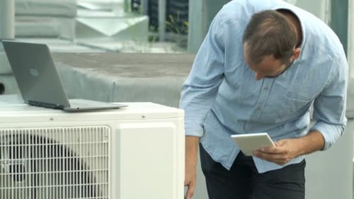 Man Uses Tablet Near Laptop on Rooftop