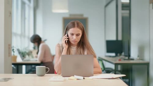Woman talking on phone while using laptop