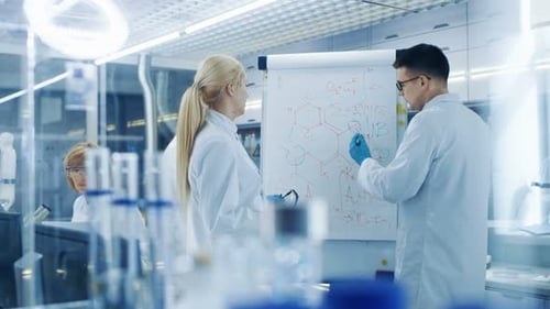 Young Female and Male Scientists Write Formulas on a Whiteboard. They're Solving Scientific Problem