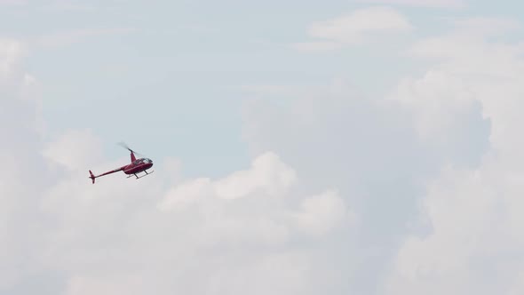 Red helicopter R44 perform stunt sky air show. Passenger chopper flying ...