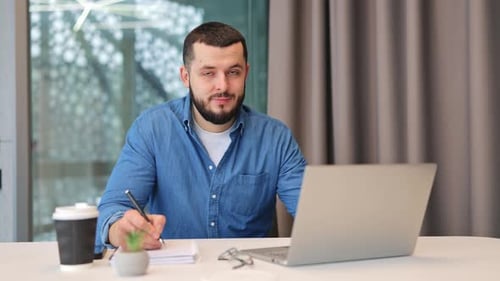 Konzentriertes professionelles Arbeiten mit Laptop und Notizblock