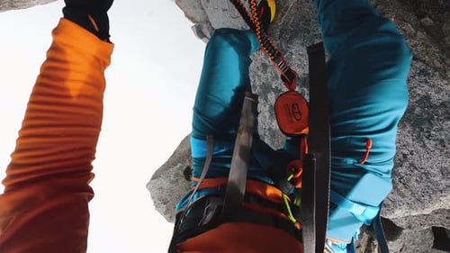 Un alpiniste descend attaché à un câble d'acier.