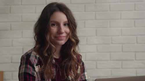 Smiling Young Woman in Front of Brick Wall
