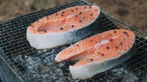 Close up of grilling salmon fillet on a smoking outdoor charcoal barbecue