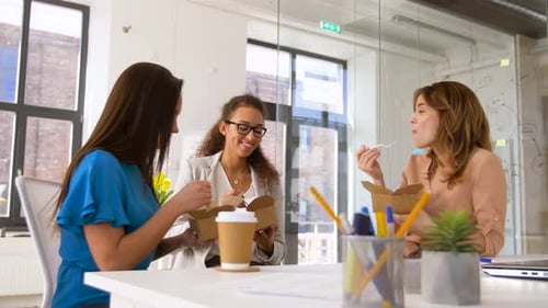 Happy businesswomen enjoying takeout lunch together at the office