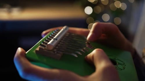 Female Musician Performing Green Kalimba Producing Gentle Melody Near Softly Glowing Christmas Light