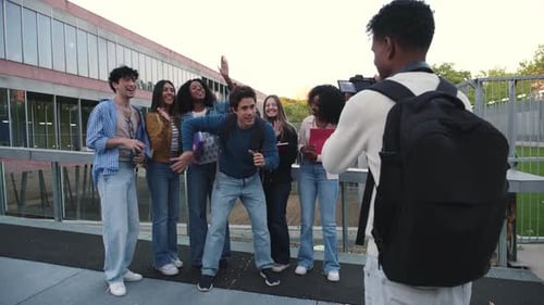 Young student dancing for friends recording video on campus