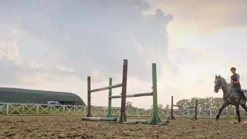 Eine Jockeyfrau springt in einem Springwettbewerb in Zeitlupe über die Barrieren auf einem Pferd