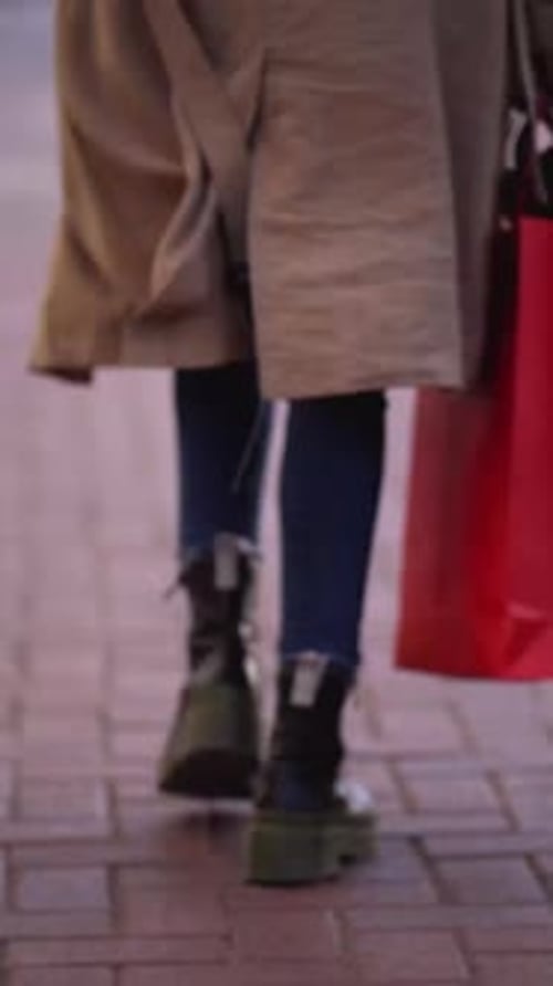Vista trasera de dos mujeres irreconocibles caminando al aire libre con bolsas de compras