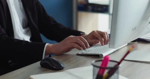 Junger chinesischer Mann mit Brille benutzt Computertippen, um im Bürogeschäft auf den Bildschirm zu schauen