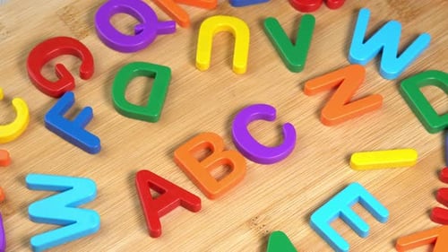 Colorful ABC Alphabet letters rotate on a wooden background. The concept of learning, school