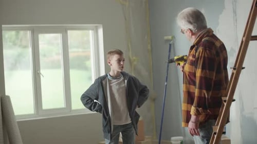 Grandpa is Showing His Grandson How an Electric Cordless Screwdriver Works