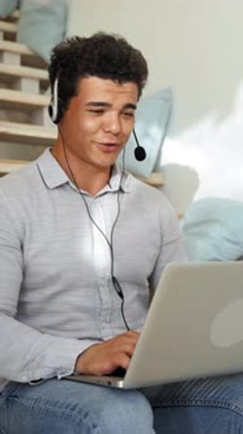 Vertical of Man Conducts Online Conference Using Headset and Laptop