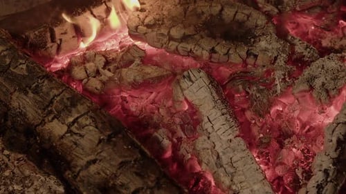 Closeup view: Red embers, hot coals in burnt down camp fire at night