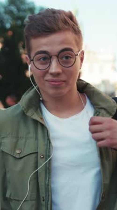 Smiling Young Adult Listens to Headphones in City