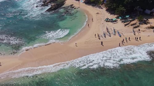 Cinematic video from above of people walking along Blue Beach in Dickwella Sri Lanka at high tide