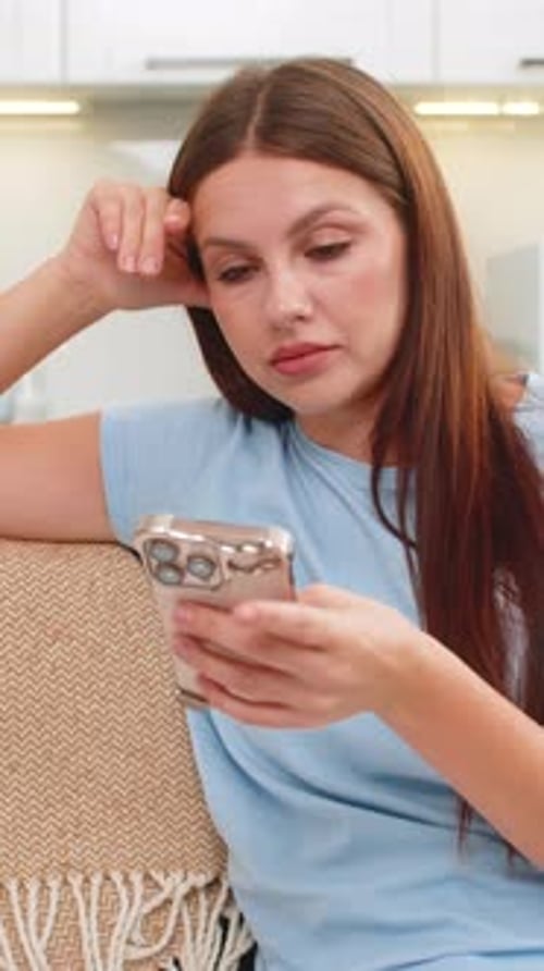 Woman Leans on Couch, Uses Phone Inside