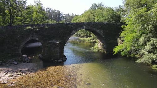 Beautiful landscape with medieval bridge and small mountain river surrounded by green trees. Perfect