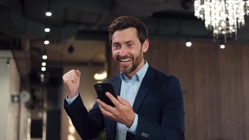 Businessman Celebrating Success While Looking at Phone