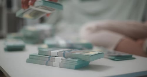 Woman Stacking Bundles of United States Currency