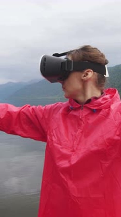 Woman Using VR Headset Outdoors by Mountain Lake