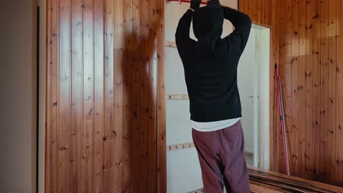 Worker removing wooden wall panels with crowbar during home renovation demolition indoors
