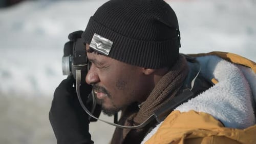 Overhead View Photographer Adjusting Camera Lens Under Winter Sun on Snowy Path