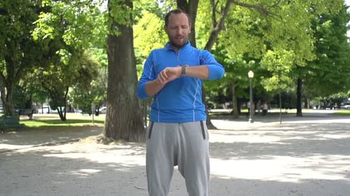 Man Checking Pulse on Smartwatch After Jogging in City Park, Super Slow