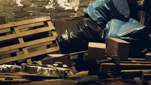 Messy Storage Area Filled with Wooden Pallets Boxes and Trash Bags at Night