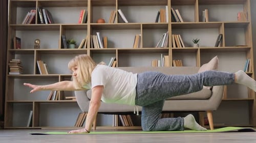 Senior Woman Doing Stretching Exercises on Mat Indoors