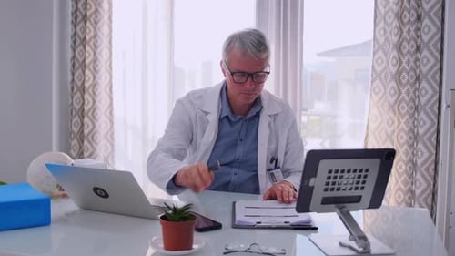 Doctor in White Coat Studying Medical Book at Desk