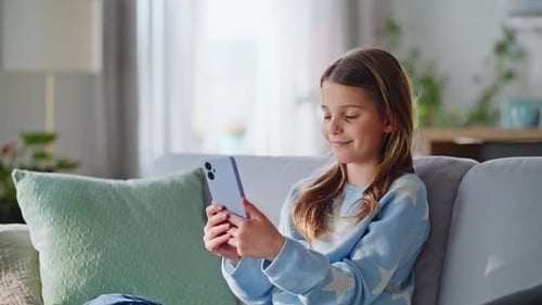 Girl Sitting on Sofa Using a Mobile Phone