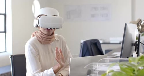 Using VR headset, woman working on laptop in modern office environment