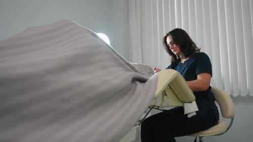 Medical Professional Prepares Examination Table in Clinic