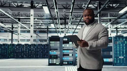 Man with Tablet Stands in Data Center