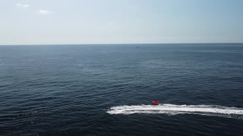 Jet Ski Pulling Tube on Ocean Near Cliffs