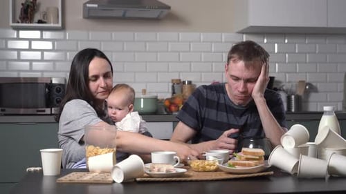Familia agotada con bebé desayunando