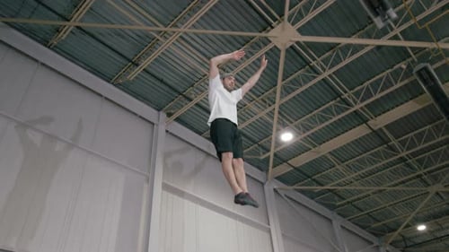 Man Performing Trampoline Stunts in Modern Gym