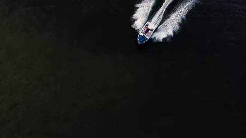Aerial drone shot following a speed boat full of people.